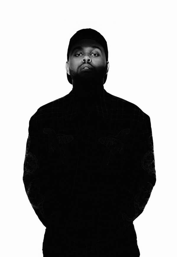 The Weeknd ganz in schwarz gekleidet vor einem weißen Hintergrund.