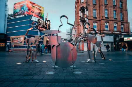 Der Beatles-Platz in Hamburg: Auf einem Platz stehen mehrere Silhouetten von Musikern. Im Hintergrund sind die Gebäude der Reeperbahn zu sehen.