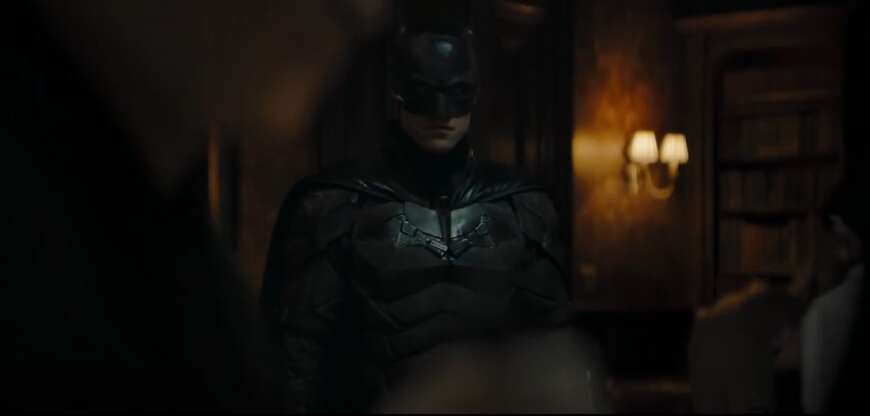 Batman steht in einem dunklen Raum.