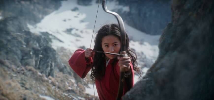 Filmszene aus Mulan: Die Kriegerin Mulan steht mit ihrem Schwert vor einer Berglandschaft.