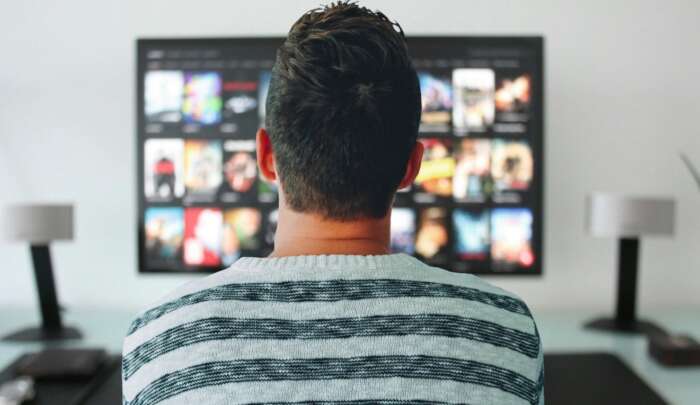 Ein Mann schaut auf einen Bildschirm, auf dem das Menü von Netflix zu sehen ist.