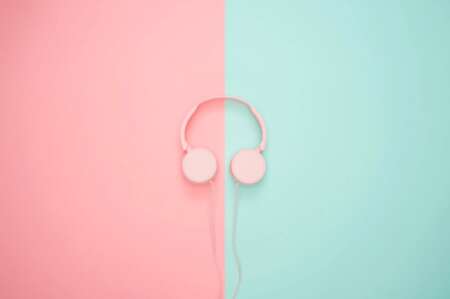 Symbolbild: Podcasts. Ein pinker Kopfhörer liegt auf einem grünen und rosanen Untergrund.