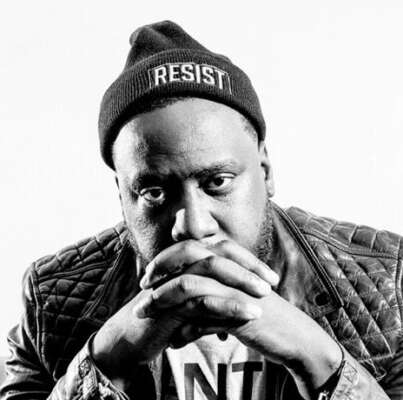 Robert Glasper schaut mit gefalteten Händen in die Kamera.
