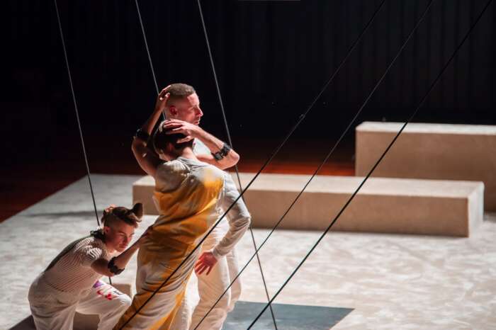 Drei Tänzer*innen stehen für das Stück „Unmute“ auf der minimalistisch gestalteten Bühne des FFT Düsseldorf.