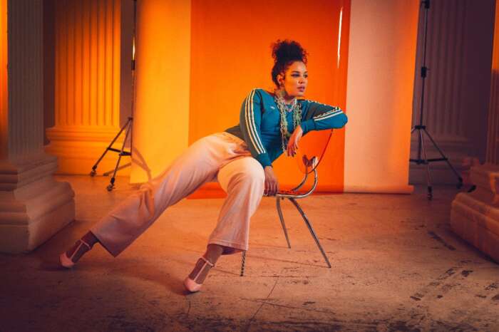 Die Hamburger Sängerin Binta auf einem Stuhl vor einem orangen Hintergrund
