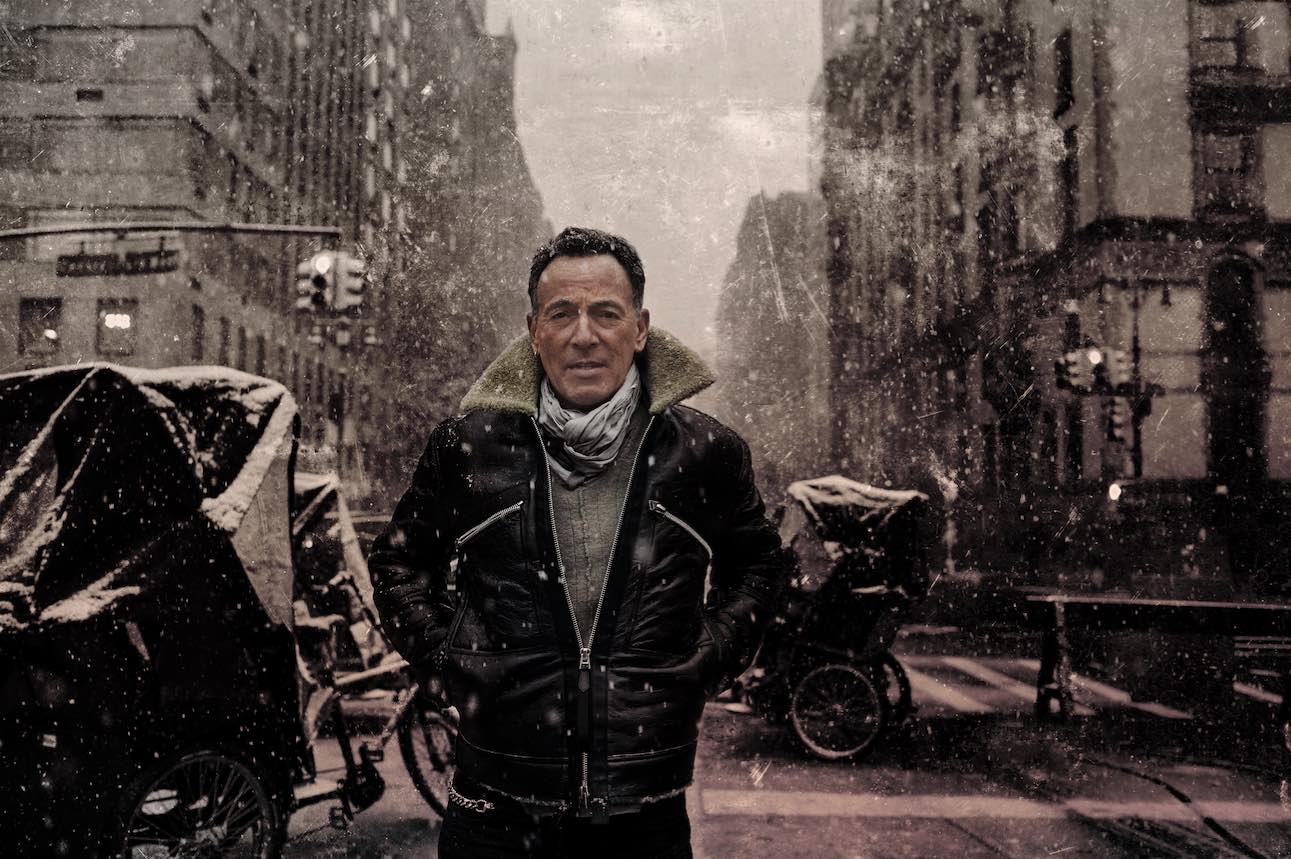 Bruce Springsteen vor einem historischen Hintergrund, gekleidet in eine Lederjacke und Schal