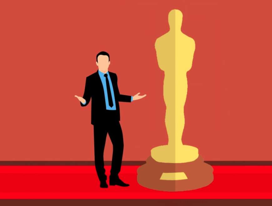 Ein Mann steht neben einer Lebensgroße Oscars-Figur.