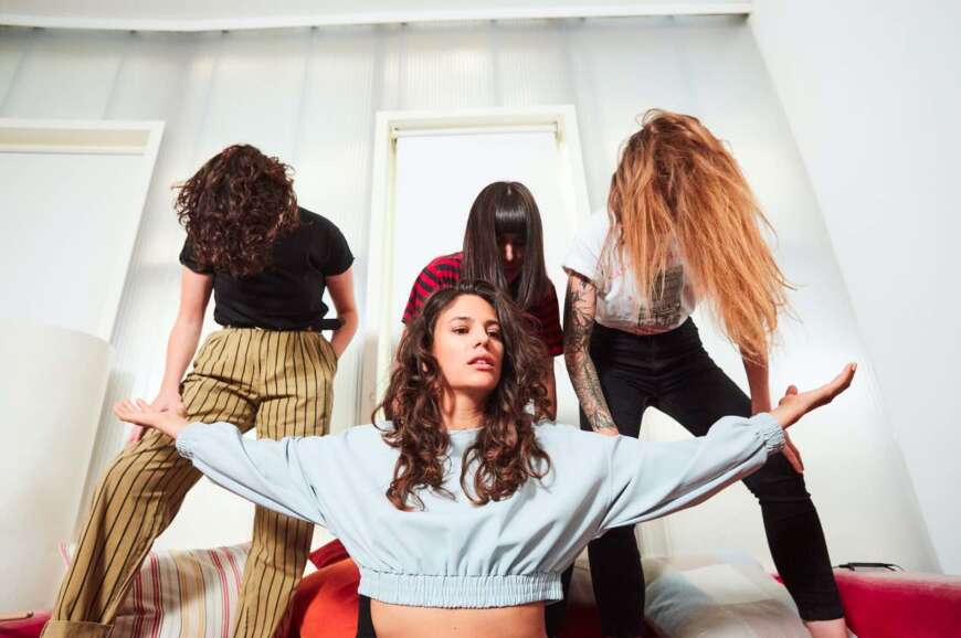 Die Band Friedberg: Sängerin Anna F. steht vor drei Personen mit langen Haaren, die vor ihren Gesichtern hängen.