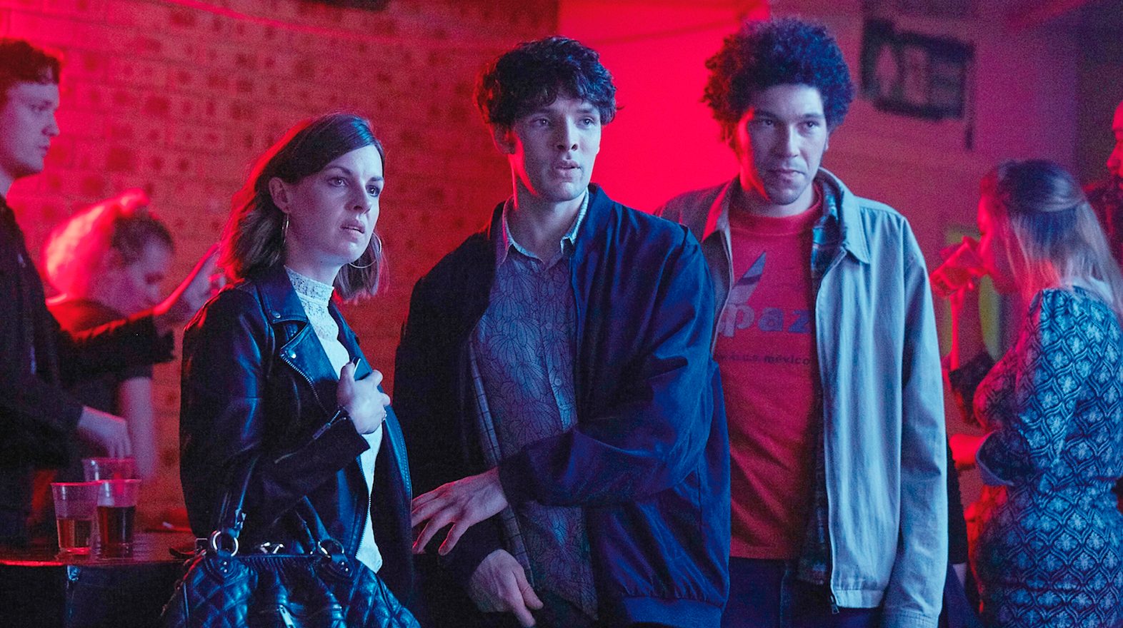 Szene aus „Benjamin“: Ein Frau und zwei Männer stehen vor einem Bartresen