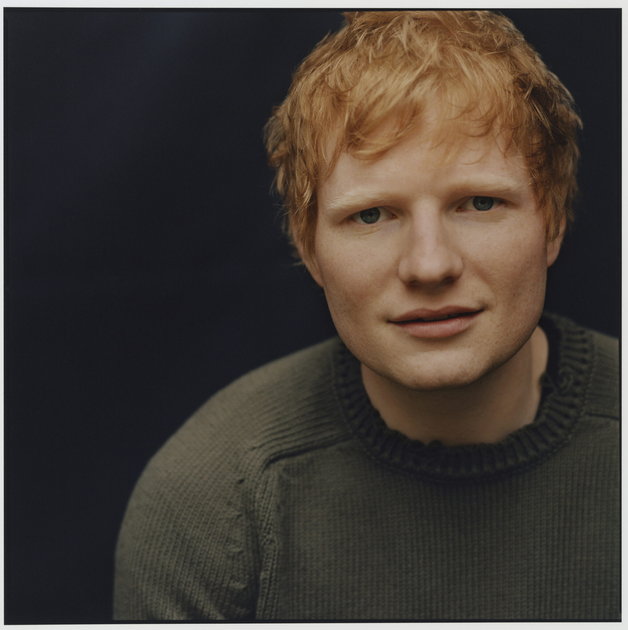 Ed Sheeran grüner Pullover schwarzer Hintergrund
