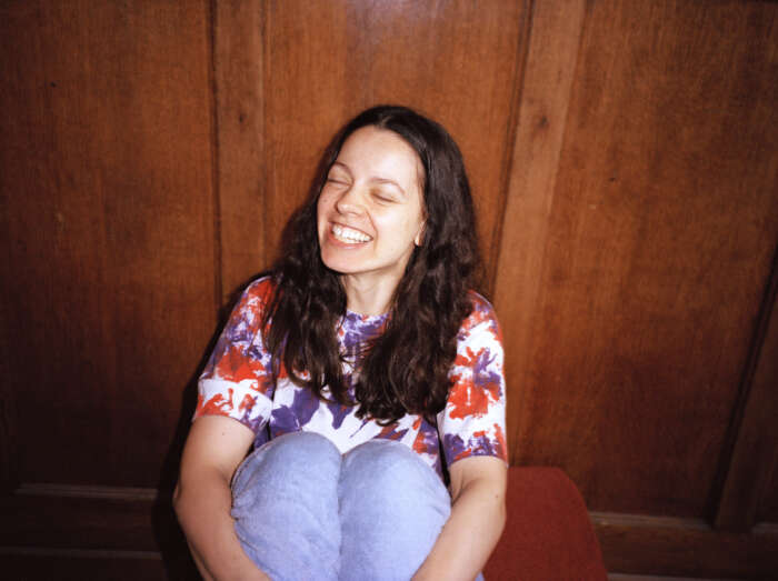 Portrait Tirzah sitzend vor Holzwand