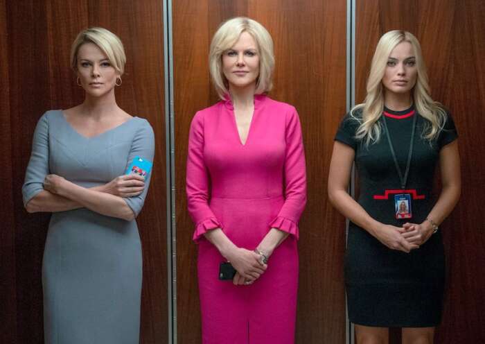 "Bombshell - Das Ende des Schweigens": Gretchen Carlson (Nicole Kidman), Megyn Kelly (Charlize Theron) und Kayla Pospisil (Margot Robbie) stehen nebeneinander in einem offenen Fahrstuhl und blicken den Betrachter an. Gretchen Carlson trägt ein auffälliges, pinkfarbenes Kleid.