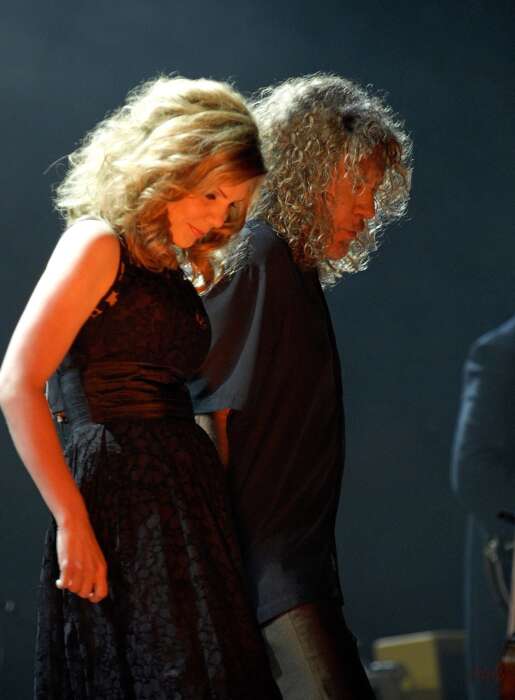 Robert Plant und Alison Kraus stehen in schwarzen Outfits nebeneinander und schauen auf den Boden.