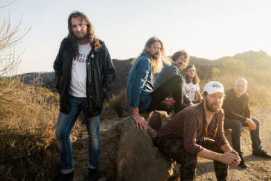 The War On Drugs sitzen und stehen in einer Steppenlandschaft.