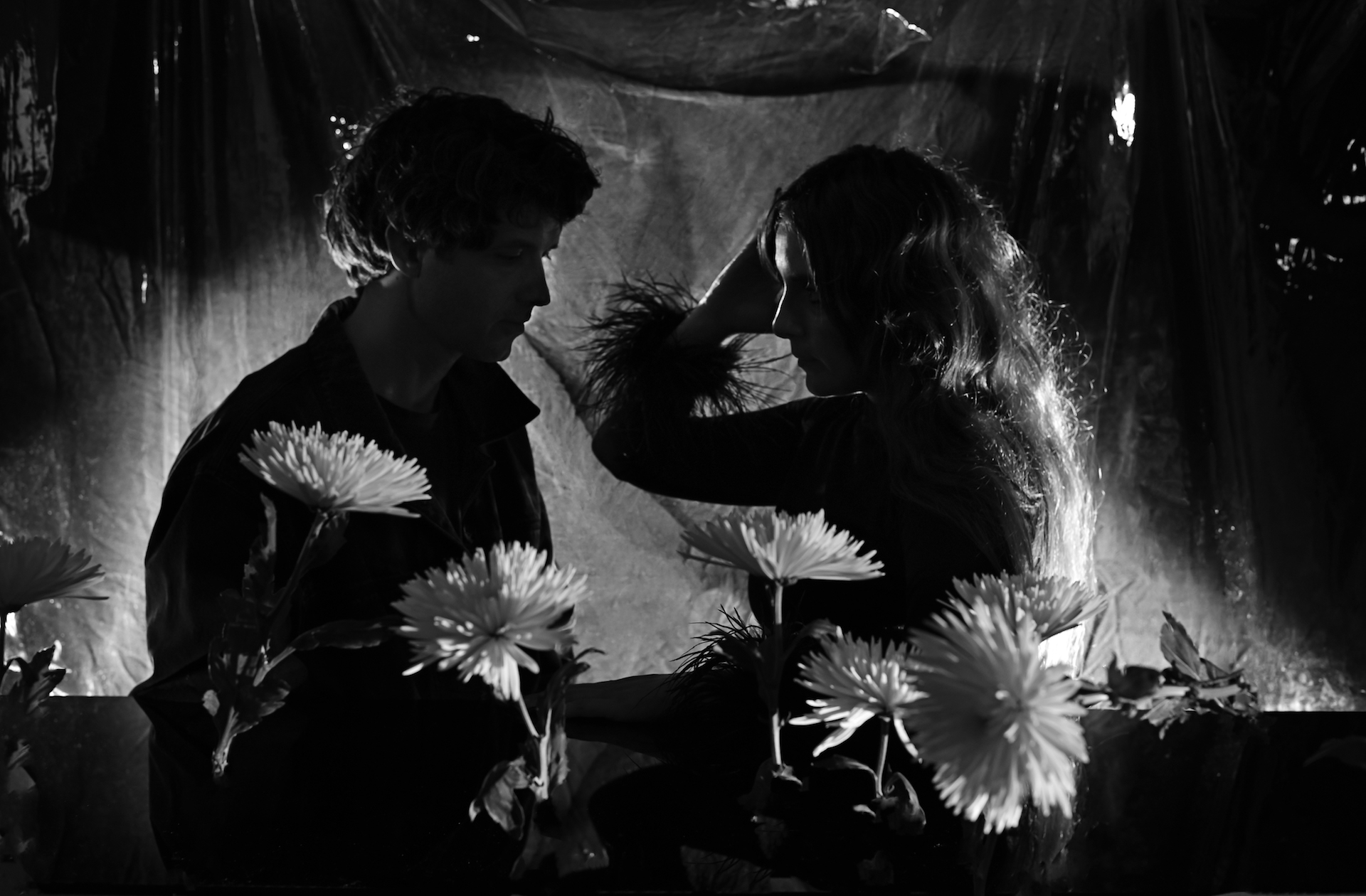 Das Duo Beach House ist anlässlich des neuen Albums „Once Twice Melody“ in einer Schwarz-Weiß-Aufnahme zu sehen, hinter weißen Blumen stehend.