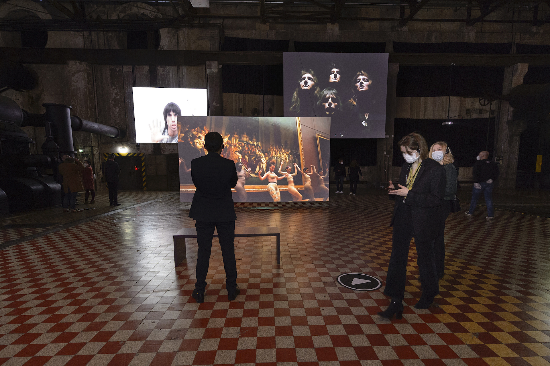 Besucherinnen, pandemiebedingt mit Maske, vor dem Video der Gruppe Queen.