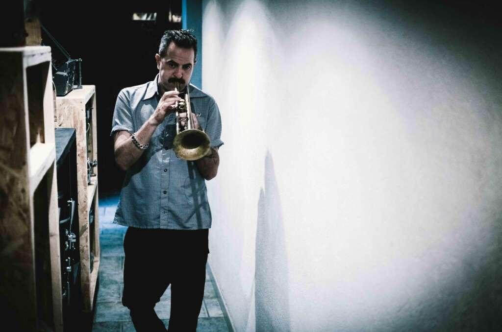 Zum Album „Naked Truth“: Avishai Cohen spielt Trompete, während er eine engen Flur hinunter geht.