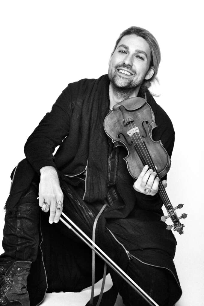 Ein Schwarz-Weiß-Foto vom Sologeiger David Garrett ist zu sehen, er hält seine Violine in der Hand.