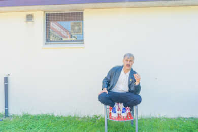Foto zu „100t Kerosin“ von Juri Volta, der auf einem groten Gartsenstuhl hockt.