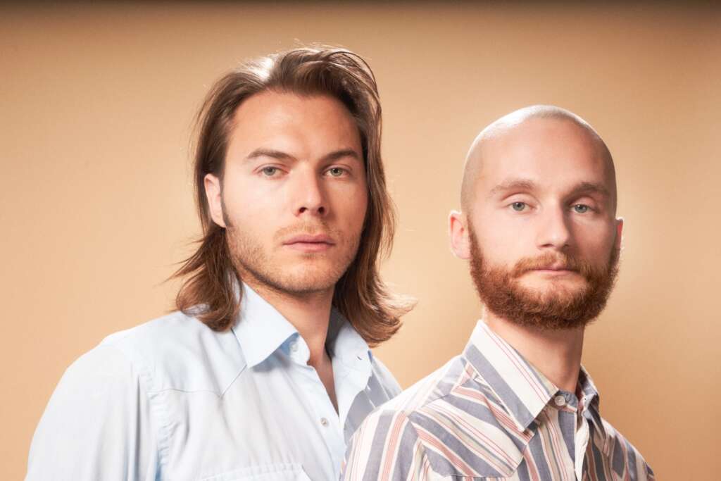 das Duo BRTHR ist in weißen Hemden zu sehen, der eine mit langen Haaren, der andere mit Glatze und Bart.