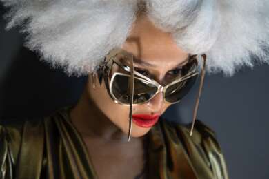 Jazzmusikerin Lady Blackbird ist mit weißen, wild gestylten Haaren und einer extraterrestrisch geformten, goldenen Sonnenbrille im Portrait zu sehen.