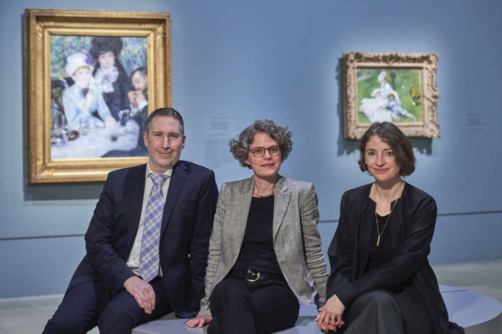 Zu sehen sind ein Mann und zwei Frauen vor Gemäden Renoirs, die das Kuratorenteam der Ausstellung „RENOIR. ROCOCO REVIVAL“ bilden.