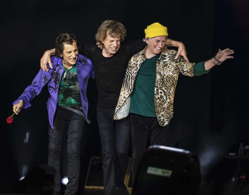 Mick Jagger, Keith Richards und Ronnie Wood von „The Rolling Stones“ lachen dem Publikum von der Bühne entgegen.