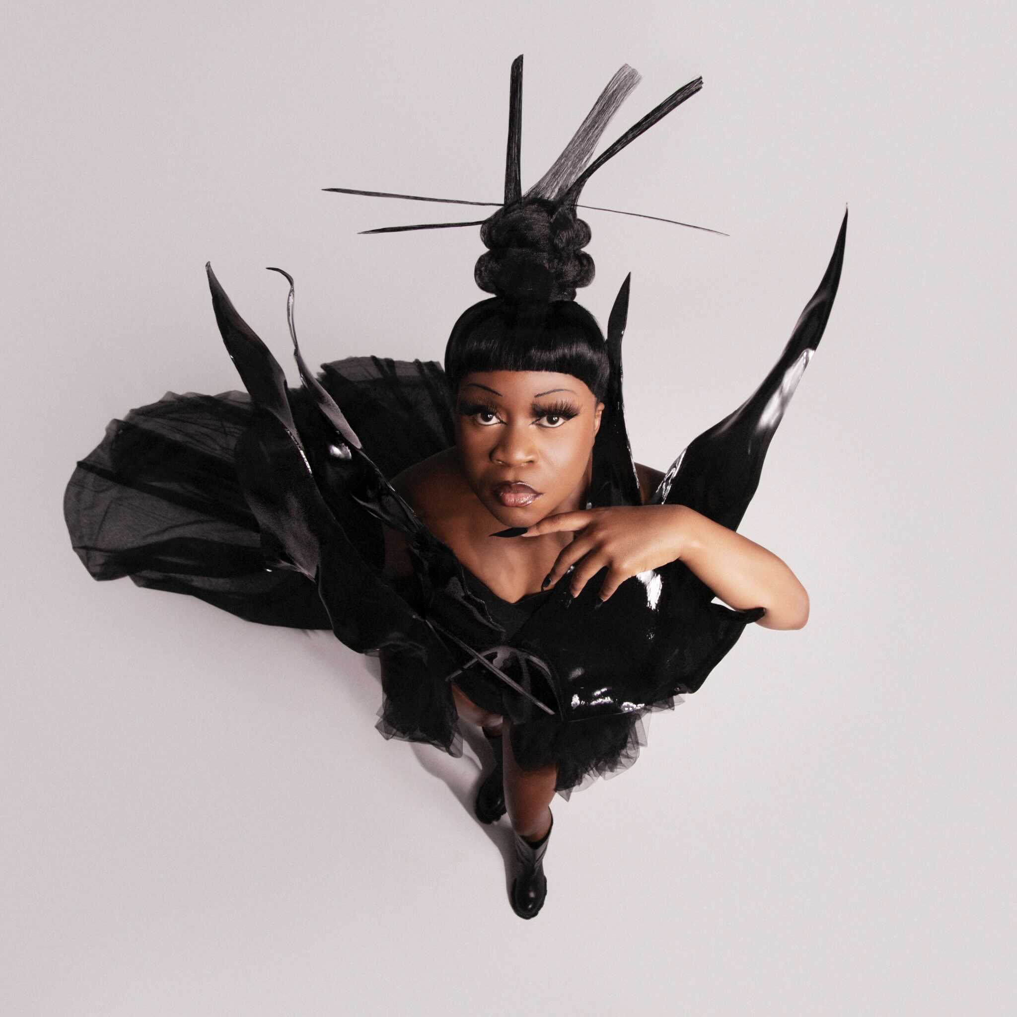 Sampa The Great in einem ausgefallenem schwarzen Dress mit Hochsteckfrisur.