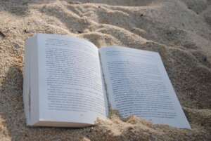 Lesungen Hamburg 2022: Zu sehen ist euch aufgeschlagenes Buch, dass am Strand im Sand liegt.