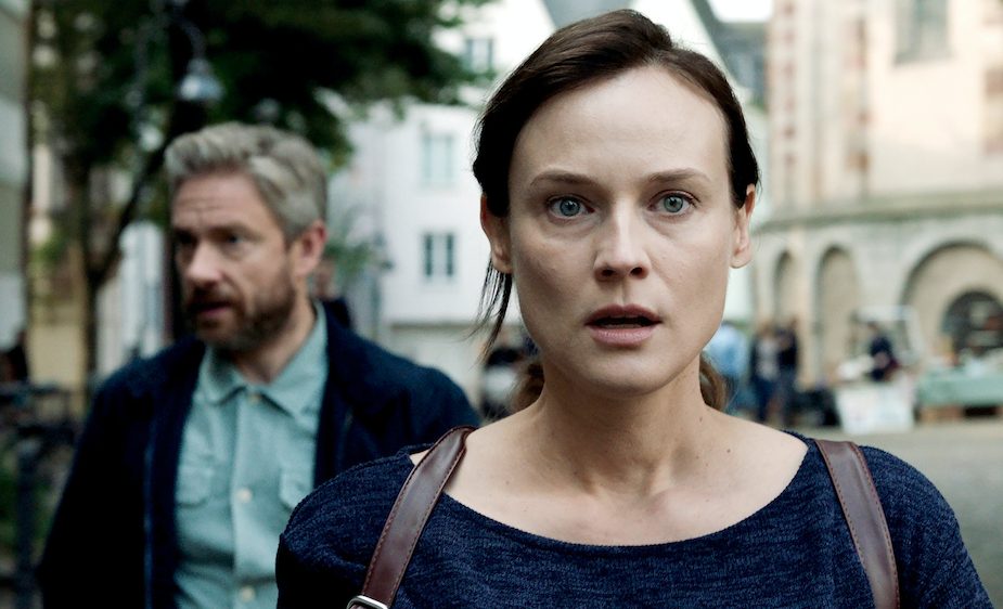 Still aus "Die Agentin": Mit erschrockenem Gesichtsausdruck und leicht erstarrt, blickt Rachel (Diane Kruger) nach vorne aus dem Bild, während dahinter Thomas Hirsch (Martin Freeman) etwas seitlich von ihr zu beobachten scheint.