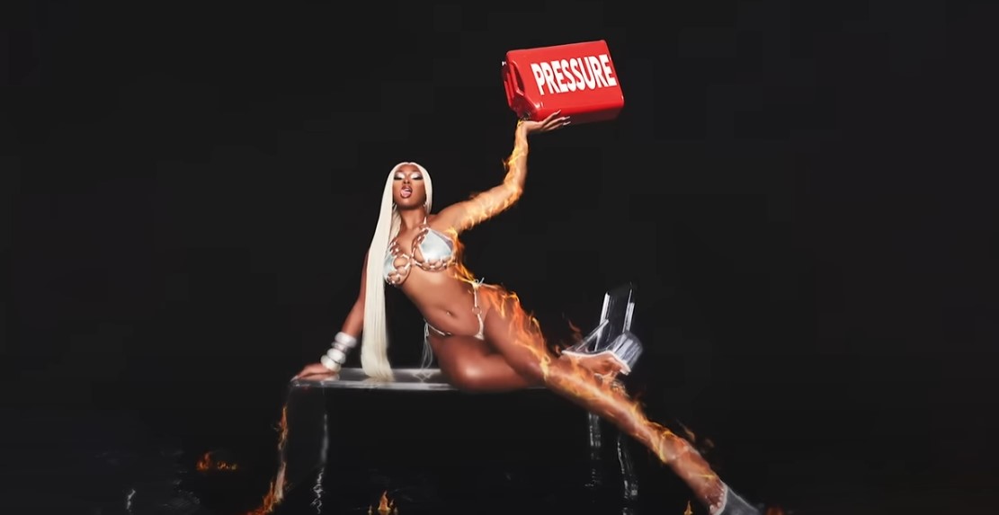 Artwork zu „Pressurelicious“: Megan Thee Stallion liegt auf einem Tisch, in einer Hand hält sie einen Benzinkanister mit dem Wort „Pressure“ darauf in die Luft