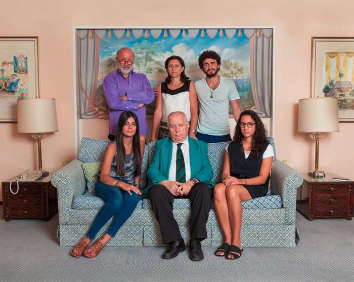 Ein Familienfoto mit sechs Personen auf und hinter einem Sofa gruppiert