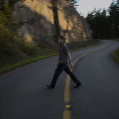 Patrick Holland geht über eine Straße in den Bergen.