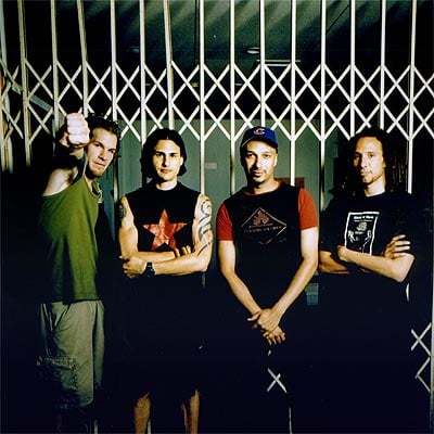 Rage against the Machine Reunion: Die vier Bandmitglieder stehen vor einem weißen Gitter.