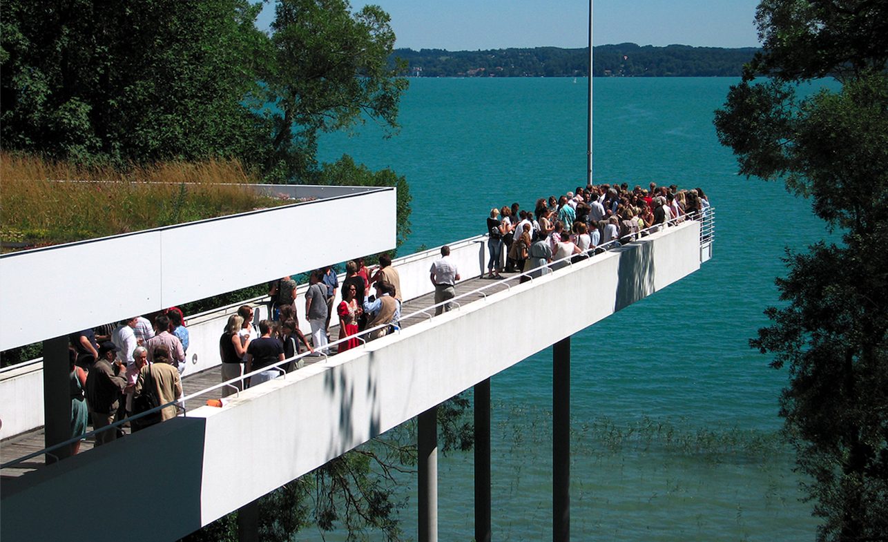Ein Steg, auf dem Menschen stehen, führt in einen See