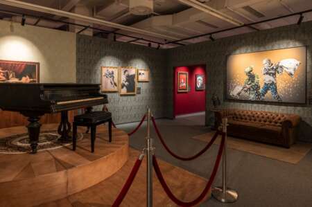 Ein Raum in einem Museum mit einem Klavier und vielen Bildern an den Wänden