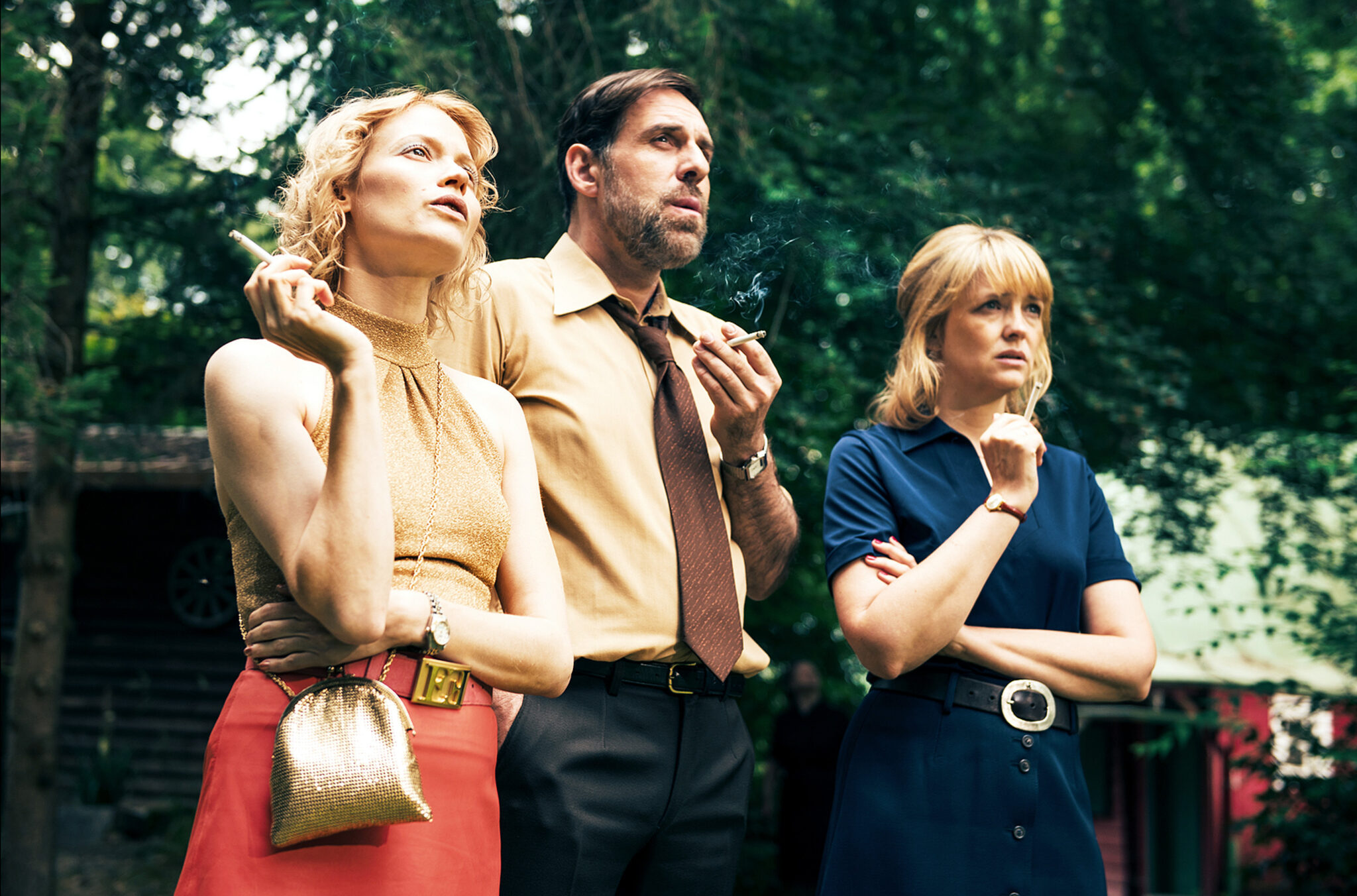 „Sommerhäuser“: V.l.n.r.: Gitti (Mavie Hörbiger), Bernd (Thomas Loibl) und Eva (Laura Tonke) stehen im Garten beisammen, sie schauen genervt.