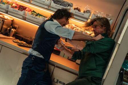 Still aus „Bullet Train“: Aaron Taylor-Johnson würgt Brad Pitt vor einem Regal mit Gebäck.