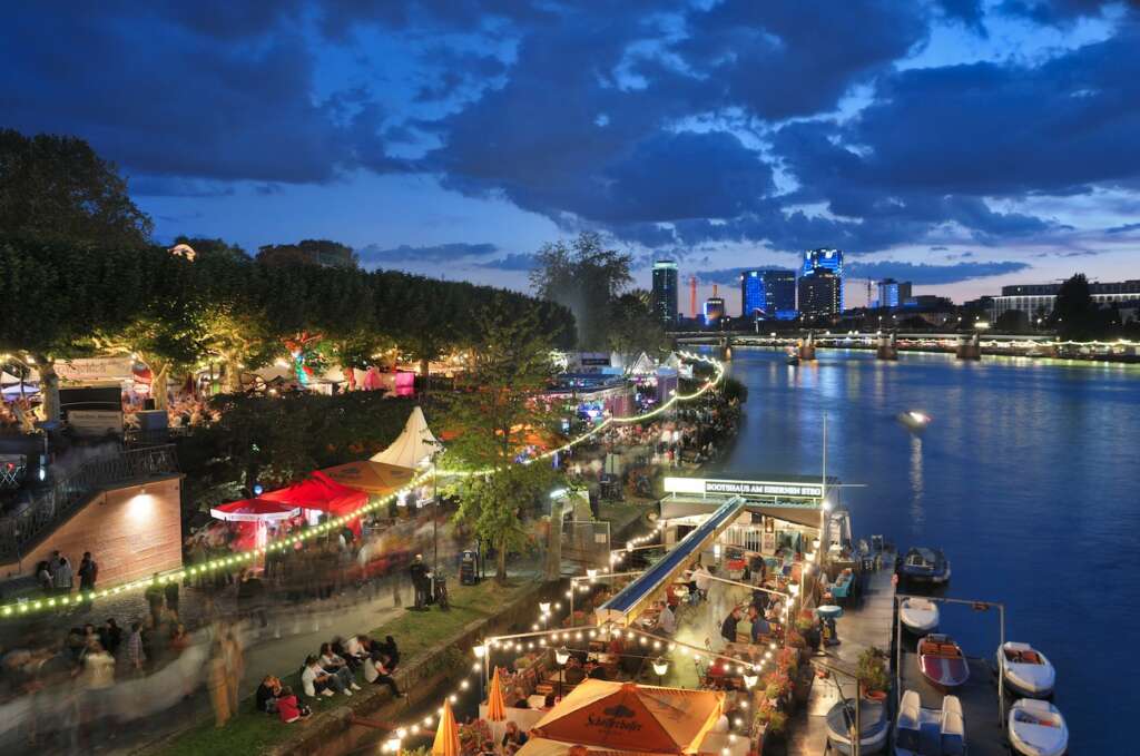 Menschen feiern abends am Ufer eines Flusses in einer Stadt