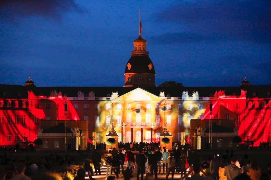 Eine Schlossfassade bei Nacht auf die Bilder projiziert sind