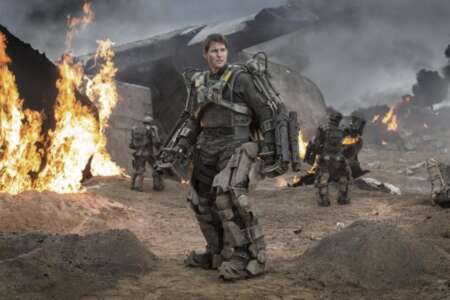 „Edge of tomorrow“: Tom Cruise steht in einem futuristischen Exoskelett auf einem Schlachtfeld. Im Hintergrund ein brennendes Flugzeugwrack.