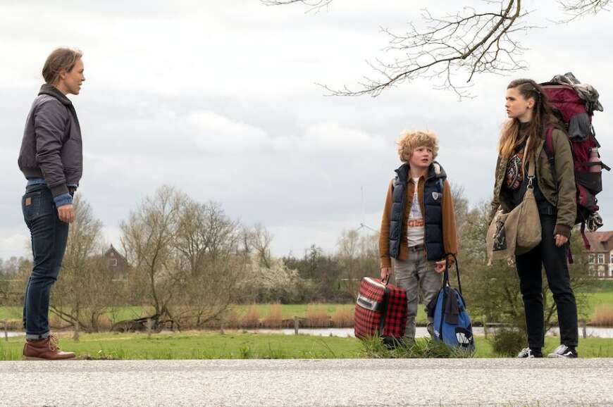 Eine Frau steht einer jüngeren Frau und einem Jungen gegenüber. Die jüngere Frau und der Junge tragen Gepäck. Im Hintergrund norddeutsche Landschaft.