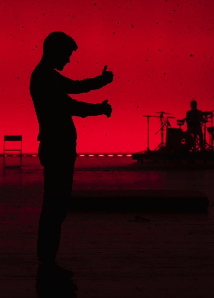 Ein Mann steht im Schatten vor einem roten Hintergrund