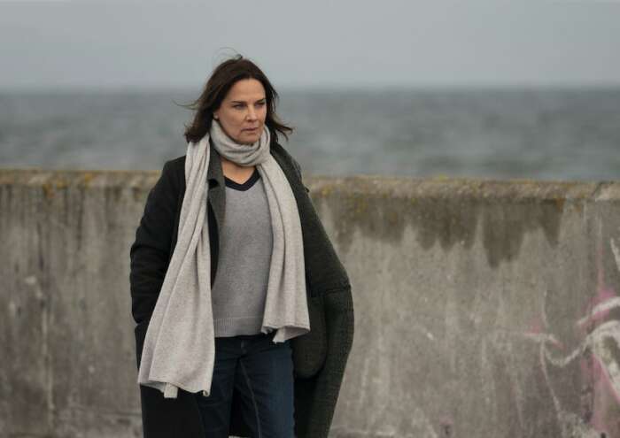 „Der Irland-Krimi: Der Preis des Schweigens: Cathrin Blake (Désirée Nosbusch) steht vor einer Zementmauer, dahinter ist das graue Meer zu sehen.