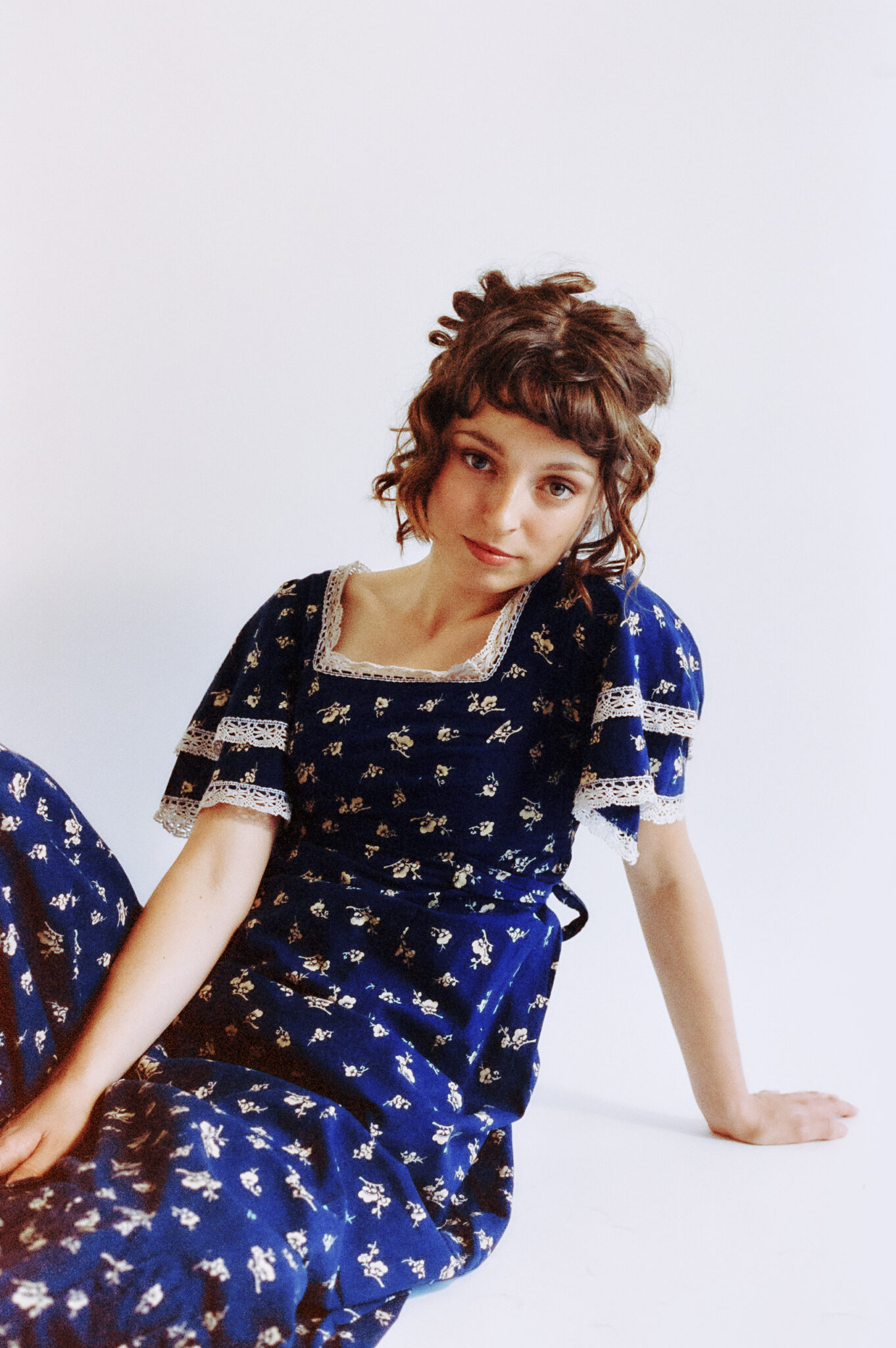 Stella Donnelly sitzend im blauweißen Sommerkleid