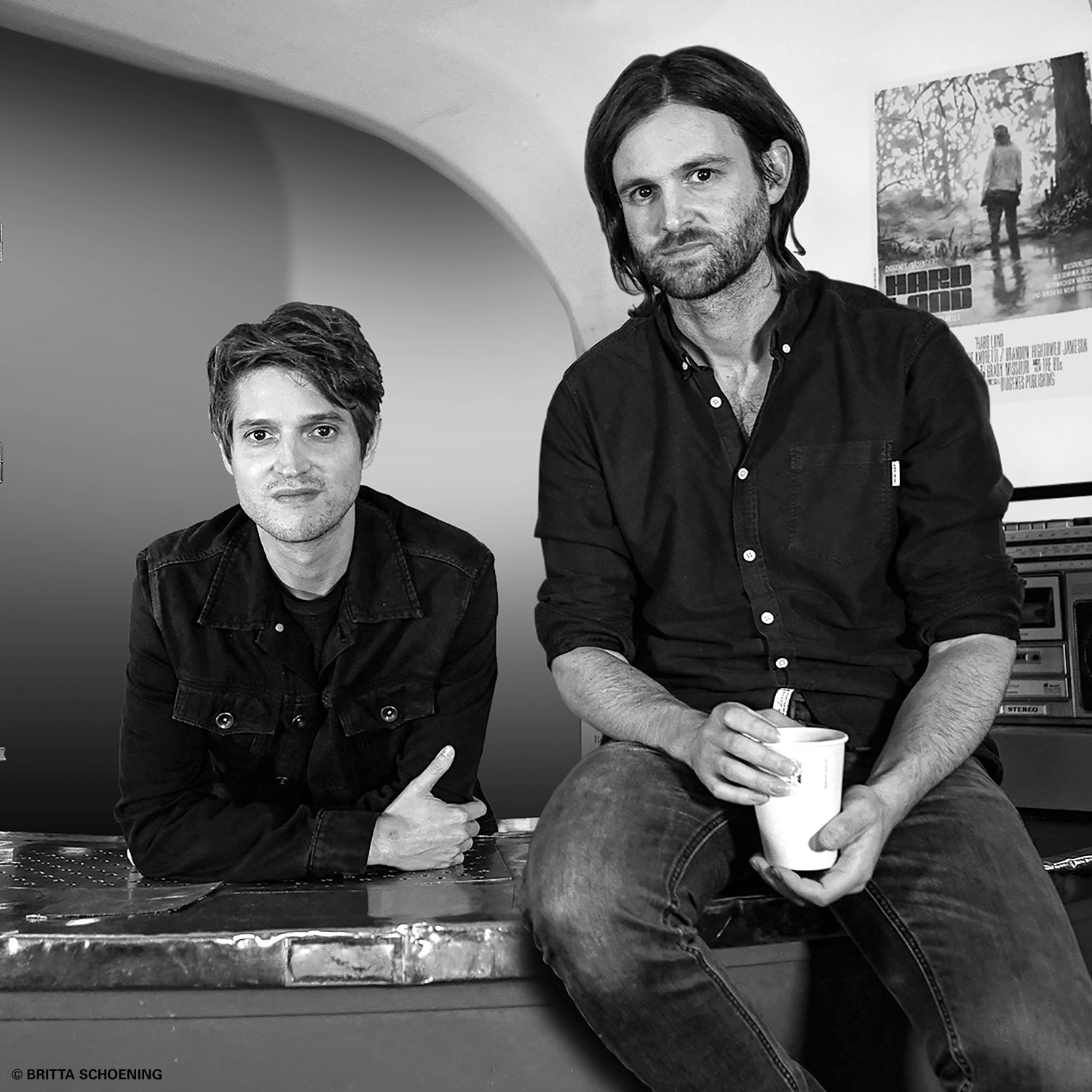 Lesereise zu „Hard Land“: Portraitfoto Benedict Wells und Jacob Brass an einer Kinokasse sitzend