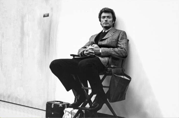 Der Schauspieler Clint Eastwood sitzt auf einem Stuhl