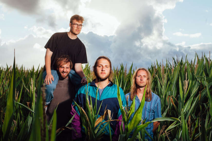 Alle vier Bandmitglieder von Il Civetto auf einer Wiese mit hohem Gras.