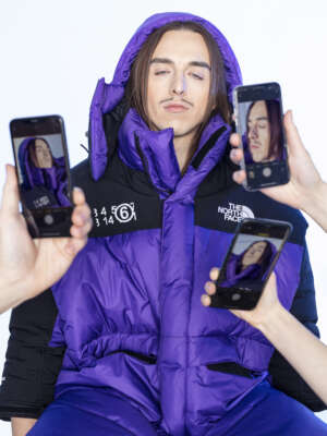 Tommy Cash mit einer lilafarbenen Jacke an. Drei Handy fotografieren ihn.