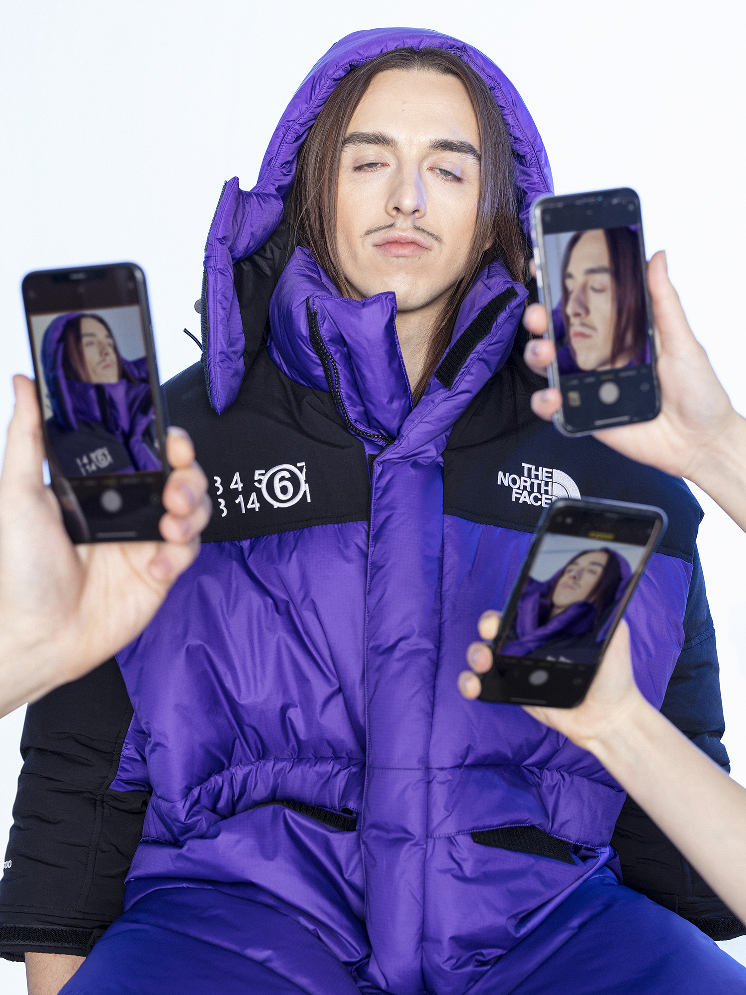 Tommy Cash mit einer lilafarbenen Jacke an. Drei Handy fotografieren ihn.